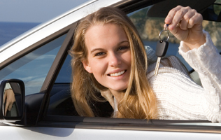 woman in a car holding up the key